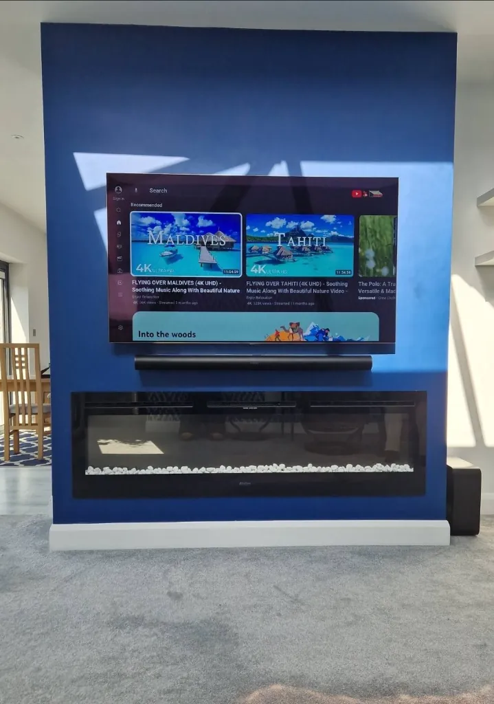 Television, soundbar and fireplace mounted on a blue feature wall