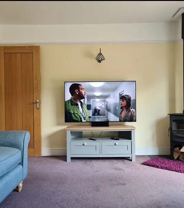 Television mounted on a wall above a grey media unit