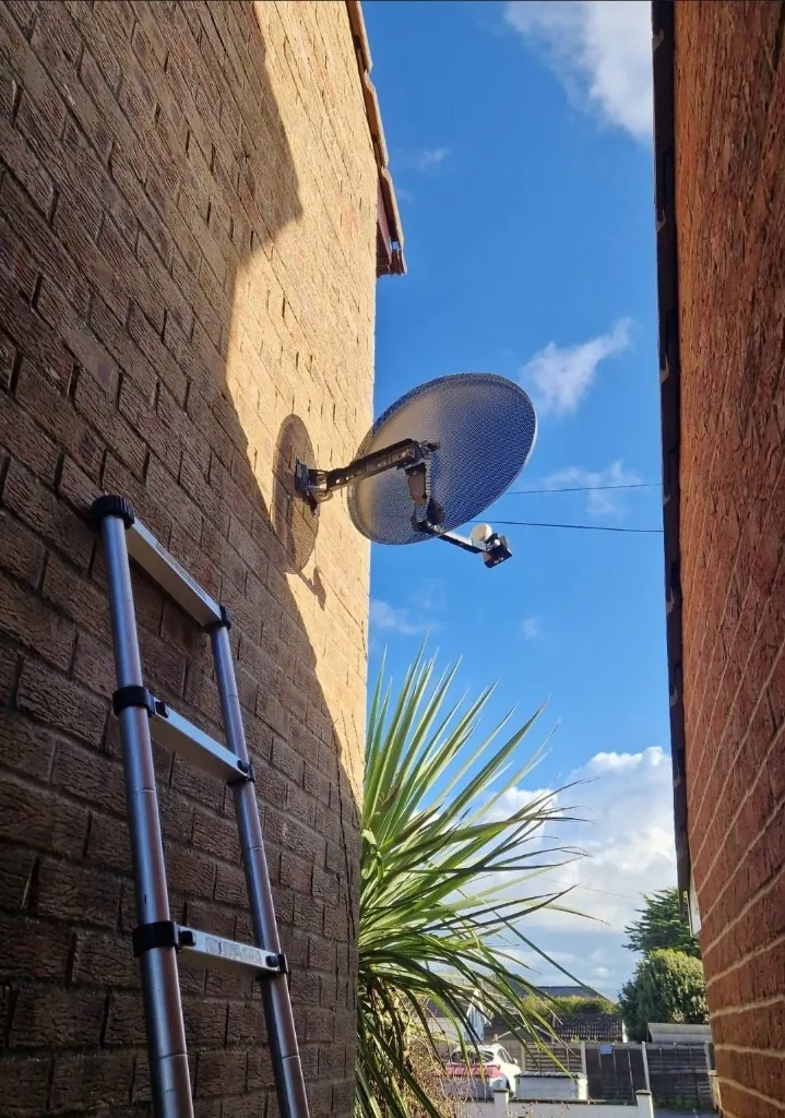 Satellite dish being installed on the exterior wall of a house